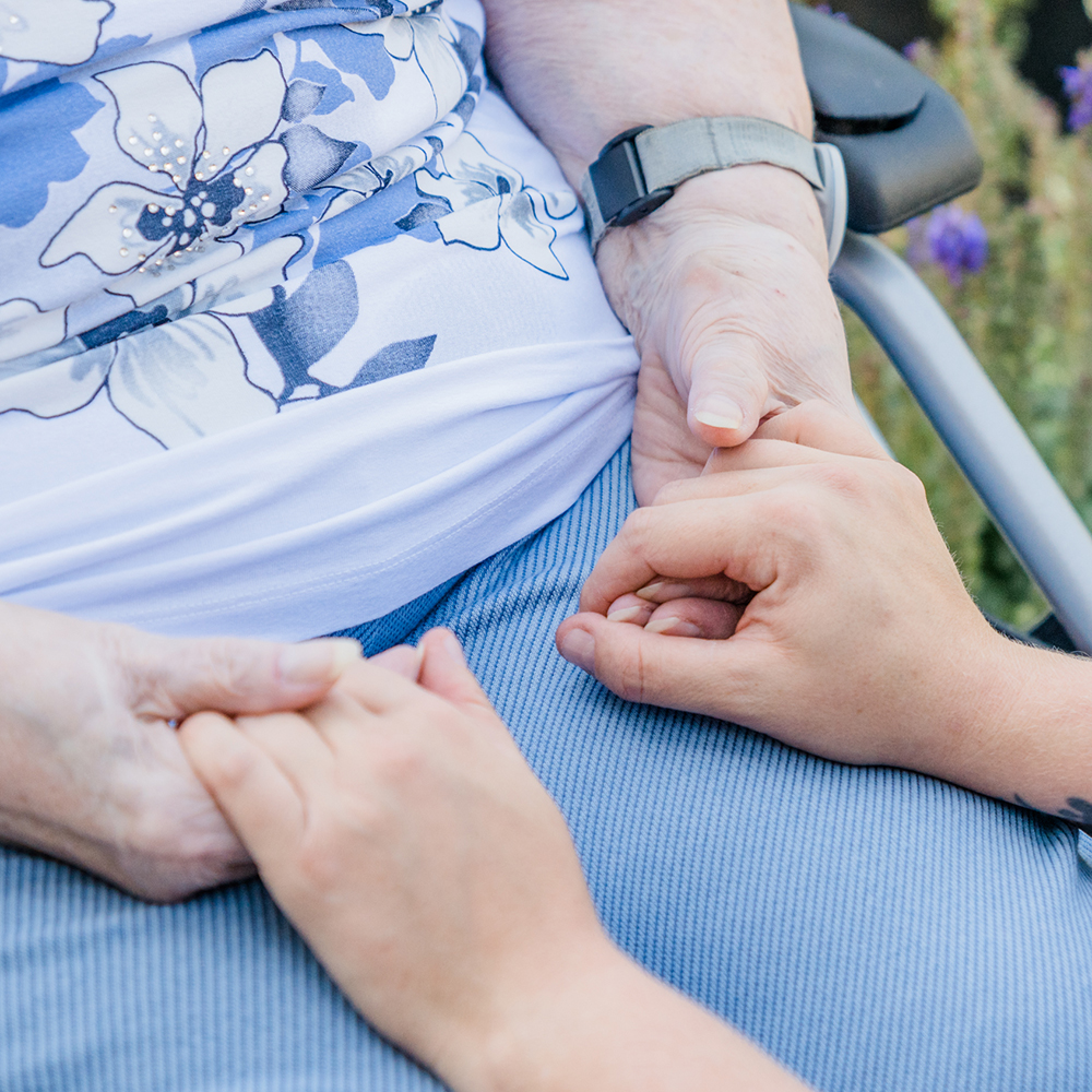 Hände eines Wohnfit Mitarbeitenden und einer Seniorin aus der Pflege bei Wohnfit